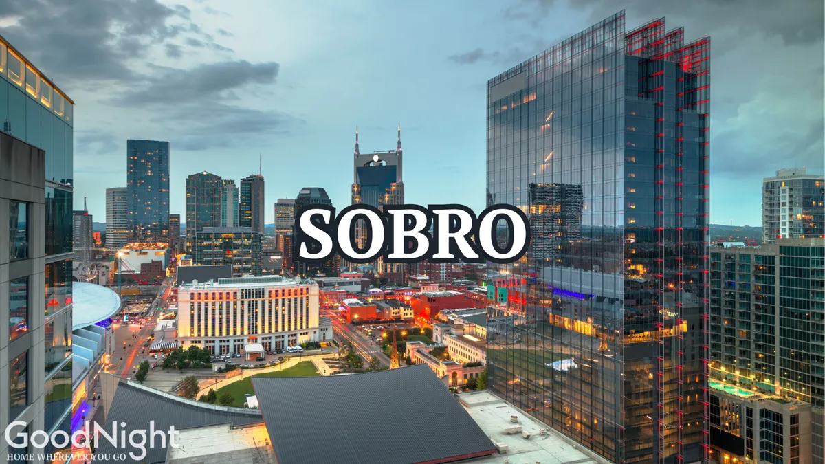 A panoramic city view featuring the Nashville skyline at sunset, illuminated by city lights and neon signage. The scene hints at nightlife, urban exploration, and the cultural heartbeat of the city, complete with prominent buildings and an inviting glow.