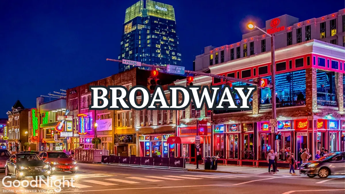 This exterior scene captures a crowded Broadway street, aglow with neon signs and lit buildings. People are out and about, with live music venues, busy sidewalks, and the vibrant energy of downtown Nashville at night on full display.