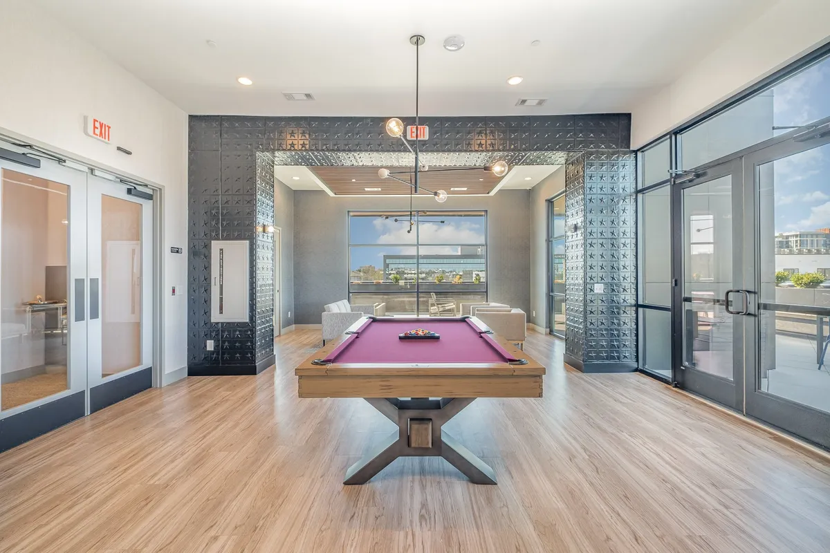 A stylish interior space that centers on a pool table, with seating areas and large windows that offer panoramic views. The environment feels lively yet relaxed, perfect for friendly games and social gatherings.