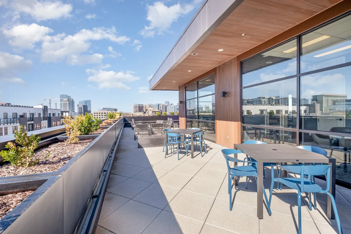 An inviting outdoor seating area with modern furniture, lush planters, and a sweeping view of the city skyline. The setting balances relaxation and sophistication, ideal for socializing or quiet reflection while enjoying city views.